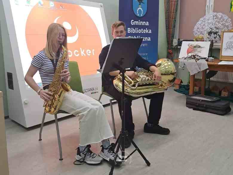 Sala konferencyjna, stoły, rollup biblioteczny, magiczna ściana, saksofon, puzon, walizka